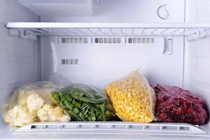 Interno di un frigorifero LG con verdure e carne confezionate su ripiano, luce bianca accesa.