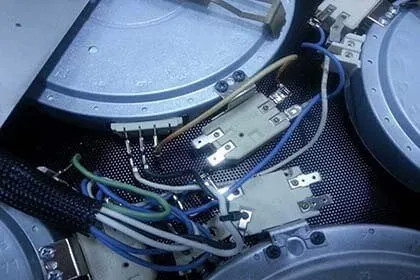 Circuito elettronico di un piano cottura LG con cavi colorati e connettori su pannello metallico, vista ravvicinata dall’alto.