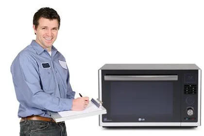 Tecnico sorridente con tuta da lavoro accanto a un forno a microonde LG su sfondo bianco.