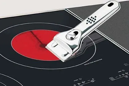 Piano cottura LG in vetroceramica con spatola metallica e padella, fuoco acceso e comandi digitali visibili.